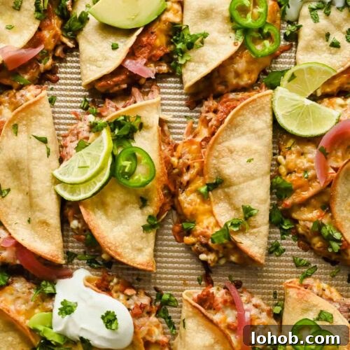baked crispy pork tacos topped with herbs, lime wedges, avocado and sour cream.