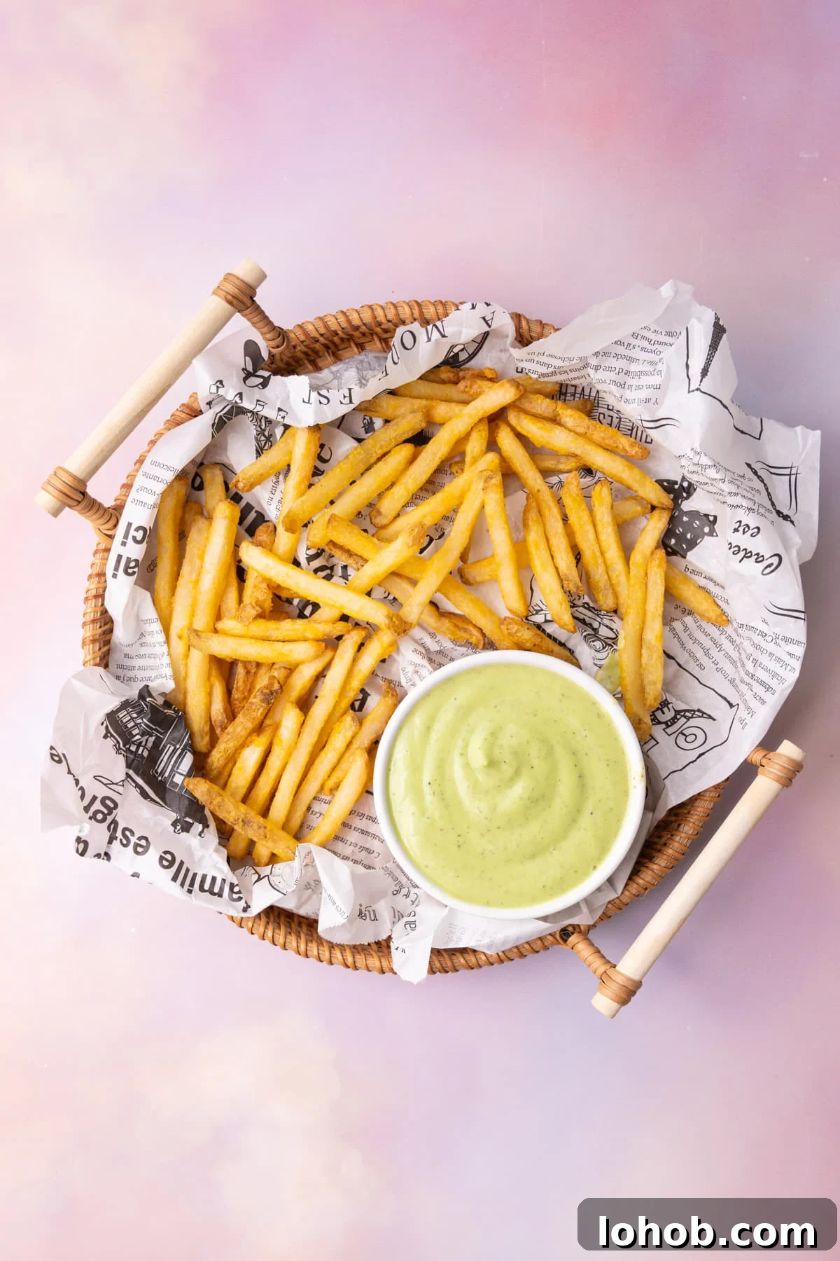 Overhead image of basket of French fries served with green avocado ranch.