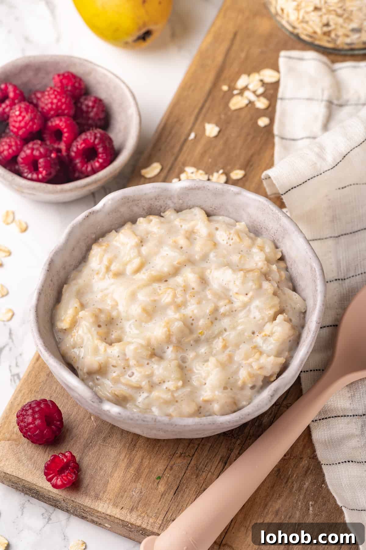 Homemade baby oatmeal is a great beginning food for infants transitioning to solid foods. Nutrient-dense, easy to digest, and simple to make! Bowl of baby oatmeal on wooden board