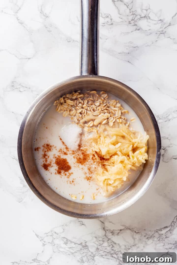 Homemade baby oatmeal is a great beginning food for infants transitioning to solid foods. Nutrient-dense, easy to digest, and simple to make! Overhead view of ingredients for baby oatmeal in saucepan