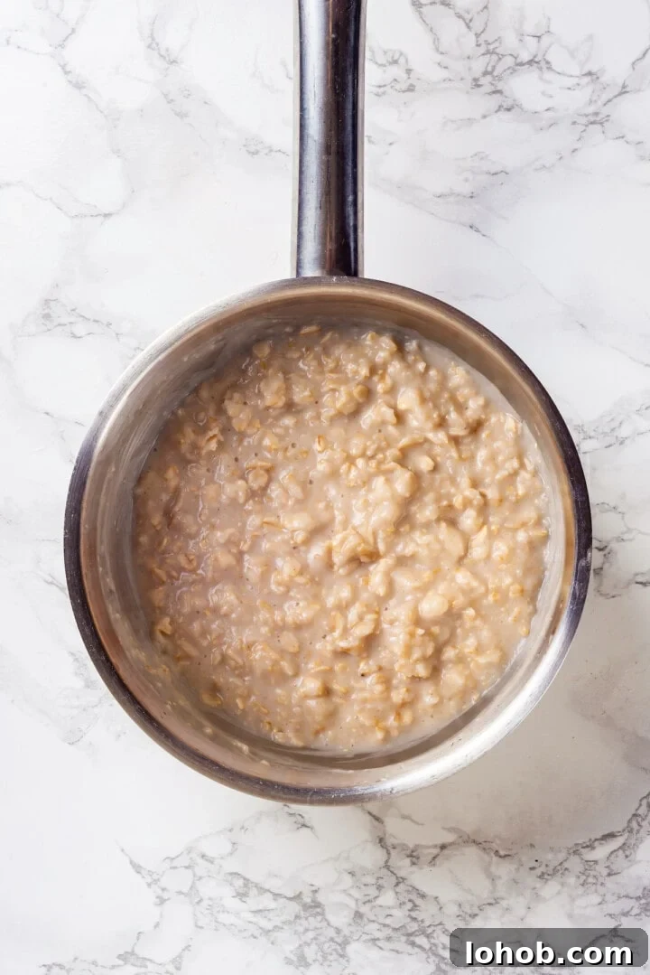Homemade baby oatmeal is a great beginning food for infants transitioning to solid foods. Nutrient-dense, easy to digest, and simple to make! Overhead view of baby oatmeal in saucepan