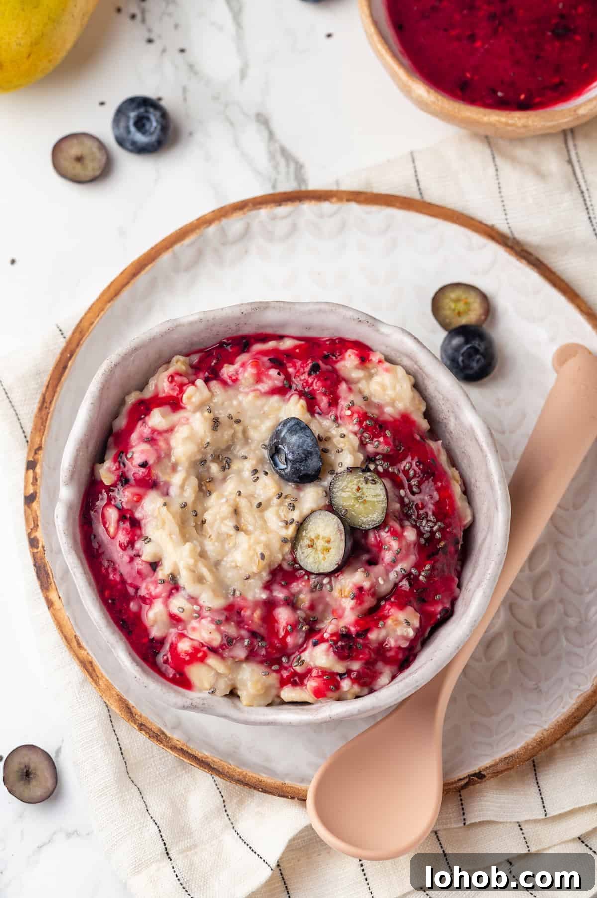 Homemade baby oatmeal is a great beginning food for infants transitioning to solid foods. Nutrient-dense, easy to digest, and simple to make! Overhead view of baby oatmeal in bowl set on plate