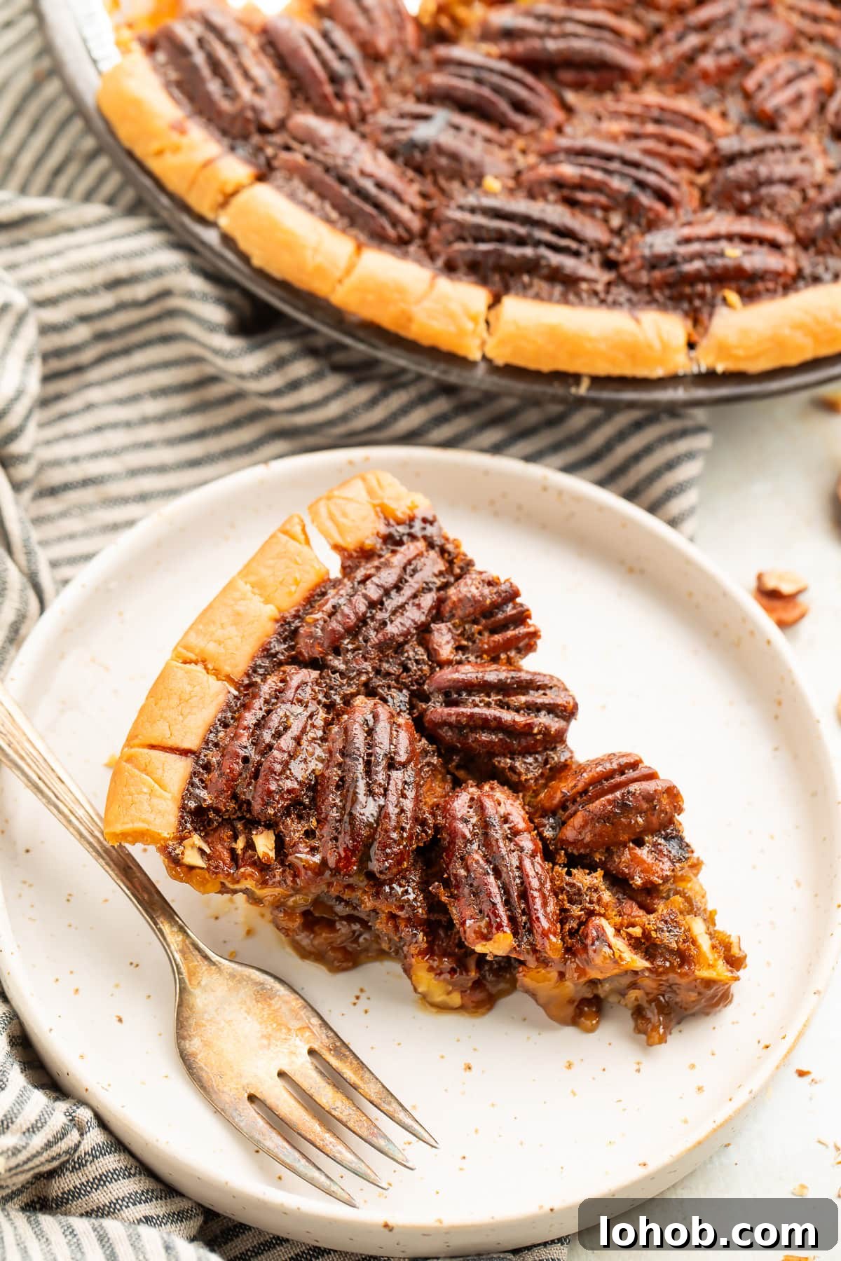 Pecan Pie Without Gluten: Classic Recipe for a Flaky Crust 2 A wedge slice of gluten free pecan pie on a plate next to the remaining pie in a pie plate.