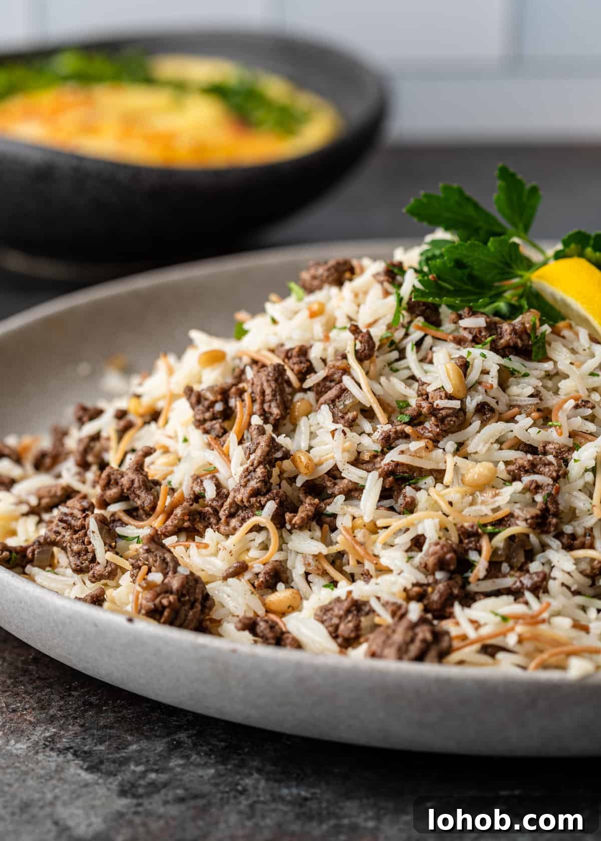 side view: a round serving platter full of my hashweh recipe over vermicelli rice and pine nuts