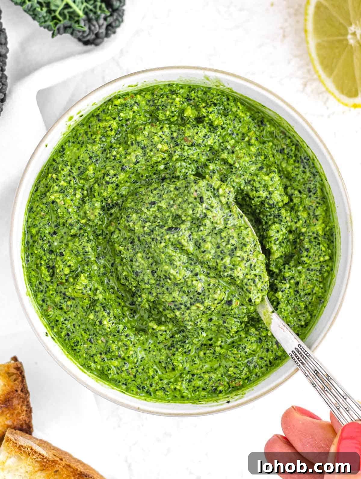 Kale Pesto Recipe: Vibrant Sauce for Pasta, Sandwiches & More 2 Kale pesto with hand and spoon