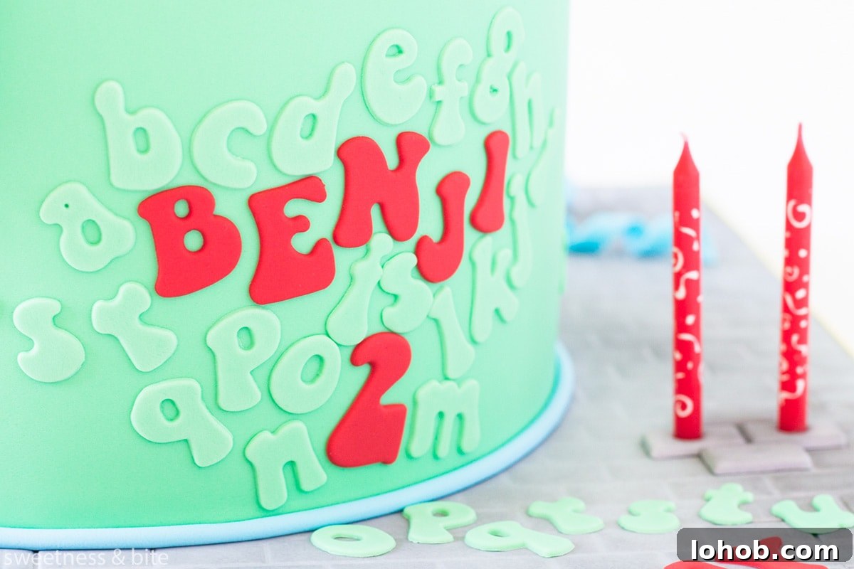 How to Adhere Fondant to Fondant: Guide to Edible Glue 3 A bright green cake with red and green lettering attached to the front. Text reads: " Benji is 2", with other alphabet letters arranged around the cake.