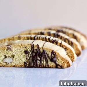 Italian almond biscotti on a white surface drizzled with chocolate.