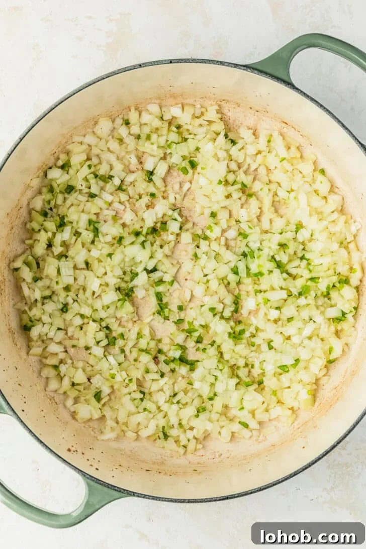 A green Dutch oven of onions and jalapenos.