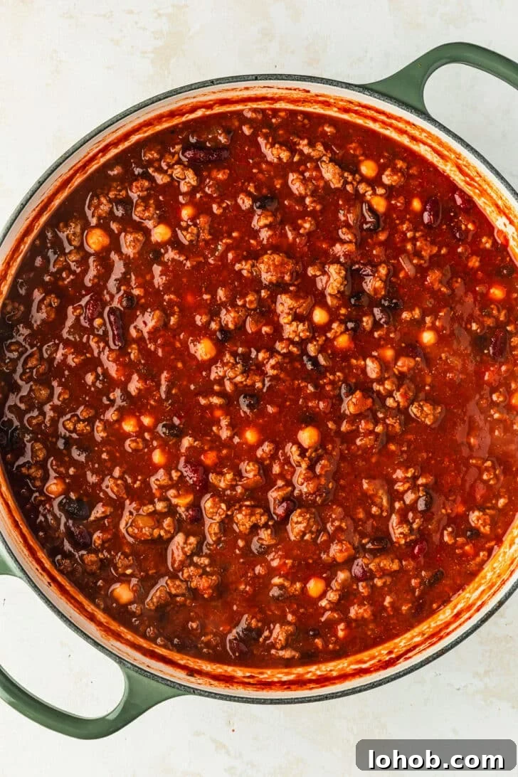 A green Dutch oven of chili for a chili toppings charcuterie board.
