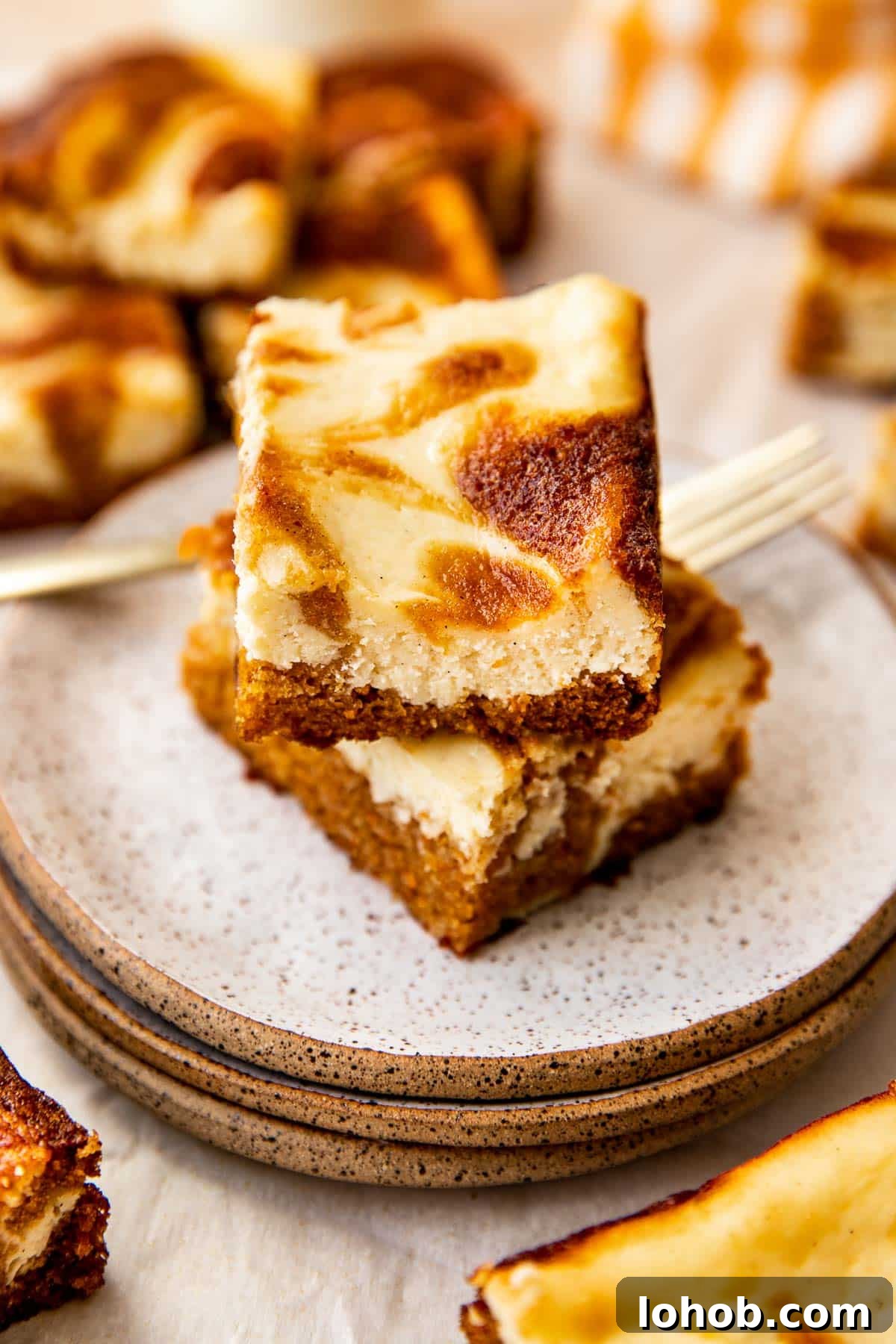 carrot cake cheesecake bars on white speckled plates. 