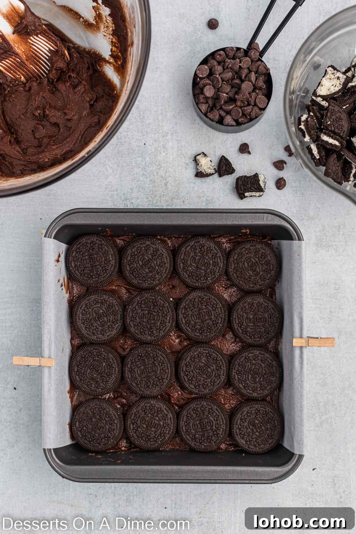 Fudgy Oreo Brownies Recipe with Creamy Cookie Filling 7 Oreo Cookies placed on top of brownie batter in pan.