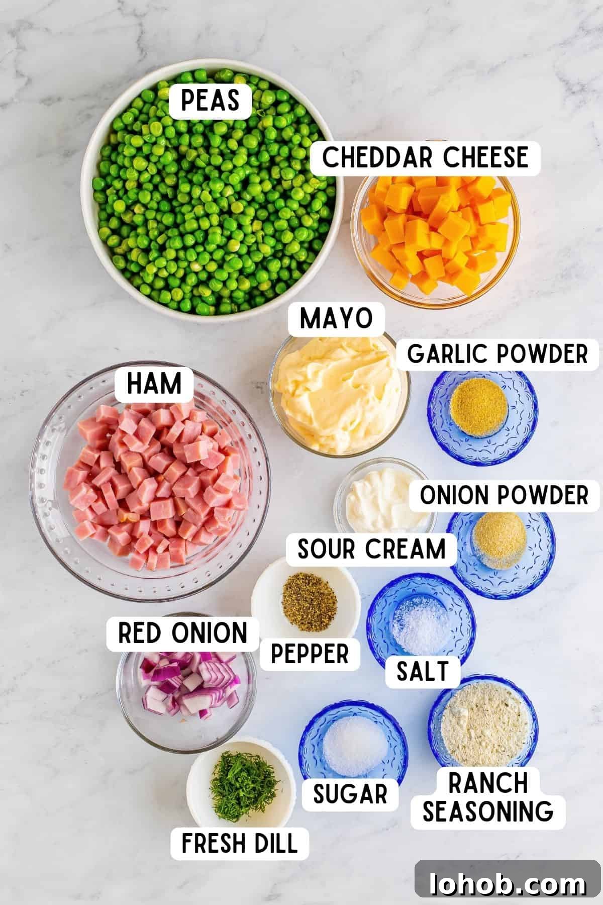 Ingredients in bowls, including: peas, cheddar cheese, ham, mayo, red onion, sour cream, onion powder, garlic powder, salt, pepper, ranch seasoning, and sugar.