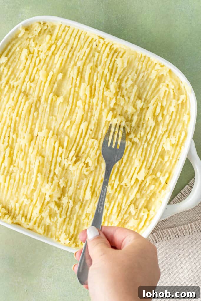 Classic Cottage Pie Recipe with Savory Beef and Mashed Potato Top 12 Using a fork to score the mashed potatoes on the pie.