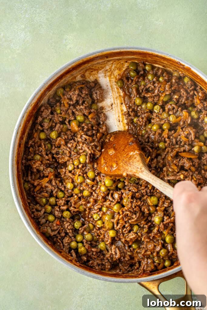 Classic Cottage Pie Recipe with Savory Beef and Mashed Potato Top 8 A wooden spoon showing the consistency of the mince mixture.