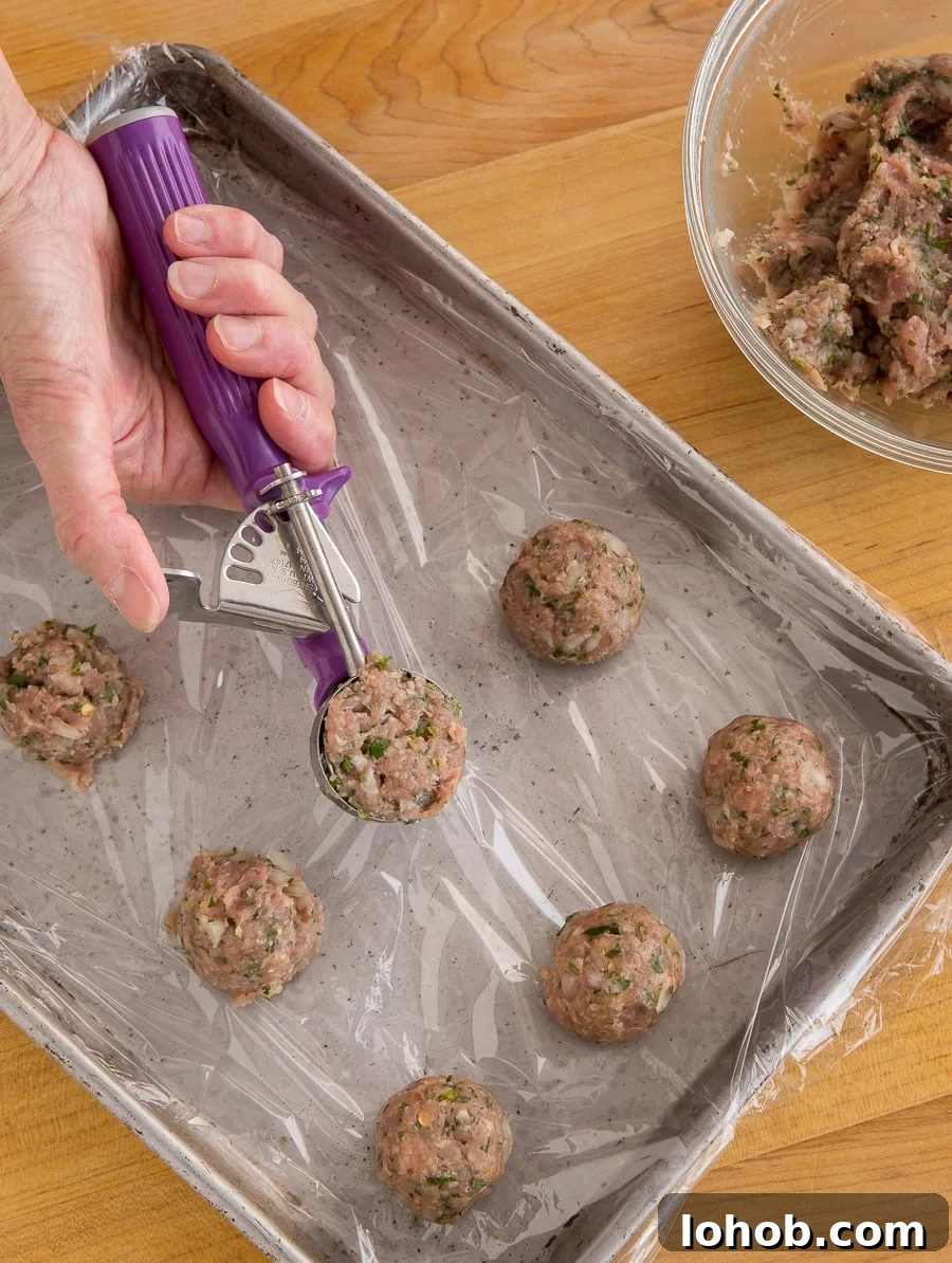 Oven-Baked Turkey Meatballs with Tangy Tomato Sauce 7 Portioning turkey meatball mix into balls with a cookie scoop onto a baking sheet.