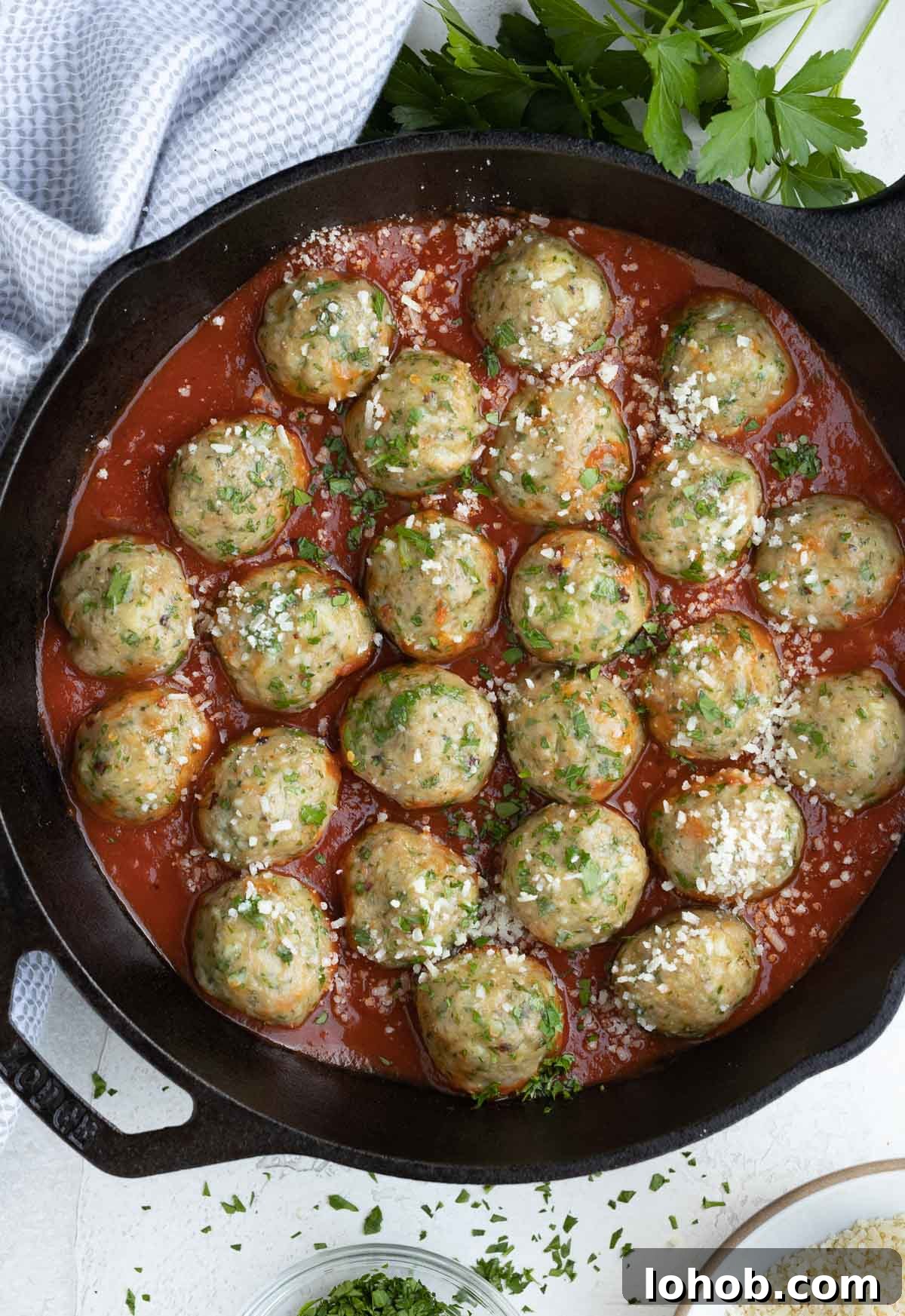 Oven-Baked Turkey Meatballs with Tangy Tomato Sauce 9 Baked turkey meatballs with red marinara sauce in a cast iron skillet.