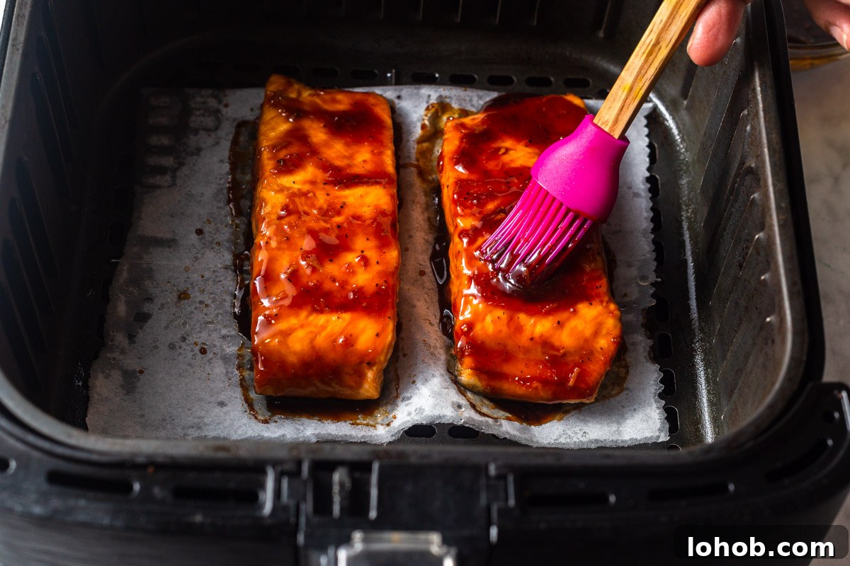 Crispy Air Fryer Teriyaki Salmon 9 brushing teriyaki sauce on the salmon.