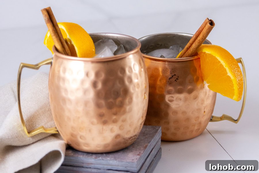 Alcohol-Free Drinks: Creative Mocktails & Refreshing Alternatives 11 two copper cups garnished with orange slices and cinnamon sticks.