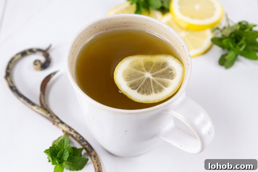 Alcohol-Free Drinks: Creative Mocktails & Refreshing Alternatives 18 horizontal crop of a mug of tea with a lemon slice in it, mint sprigs around the mug.