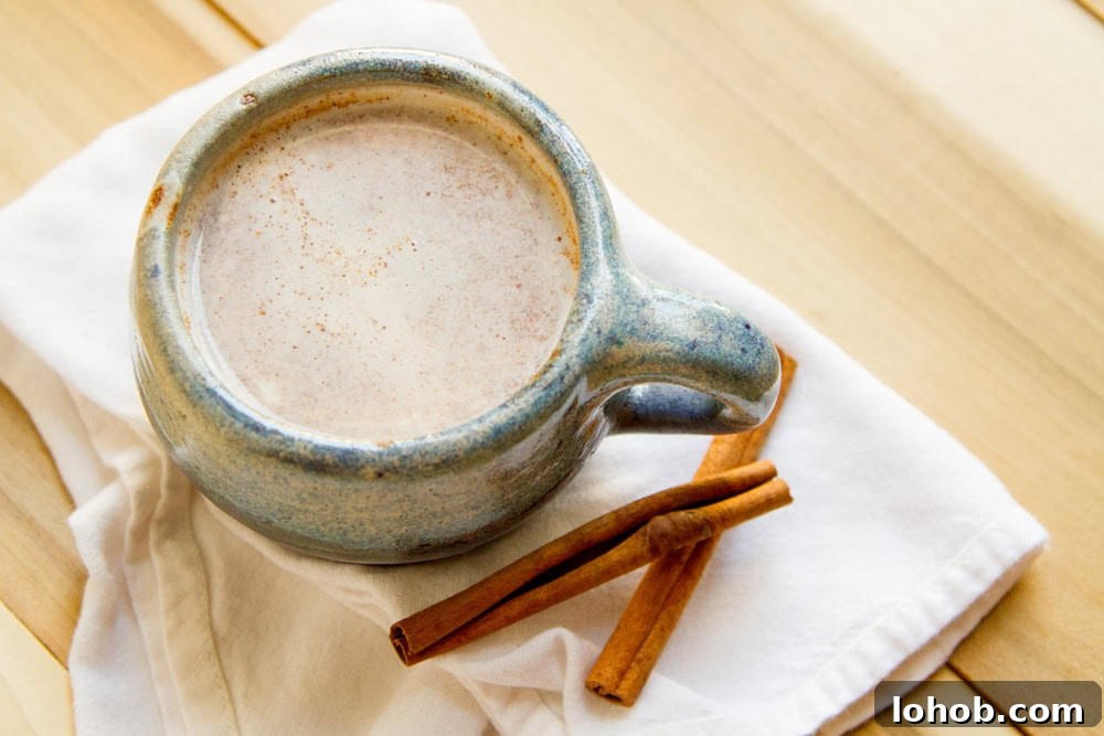 Alcohol-Free Drinks: Creative Mocktails & Refreshing Alternatives 3 a blue ceramic mug filled with creamy drink and two cinnamon sticks next to the mug.