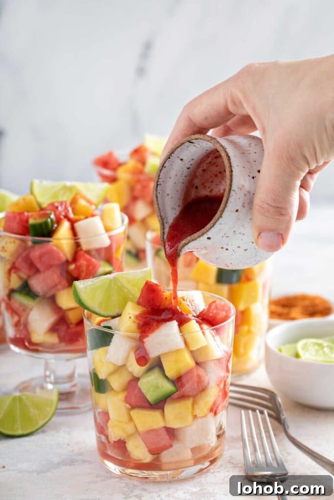 Pouring Mexican chamoy sauce over a cup of fresh fruit