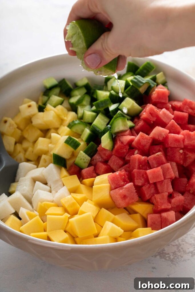Squeezing lime juice over a bowl of chopped fruit