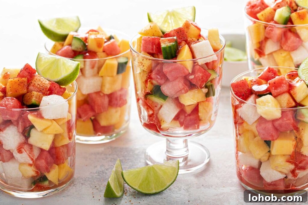 Several cups filled with chopped fruit, garnished with lime wedges