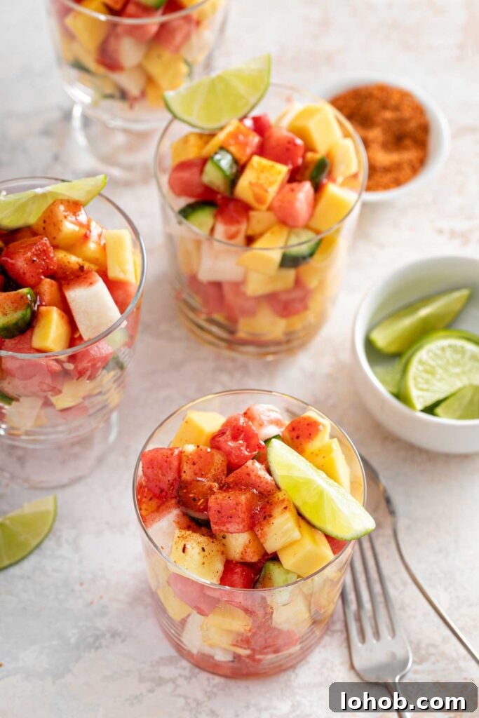 Cups filled with chopped fruit pieces seasoned with tajin and chamoy sauce