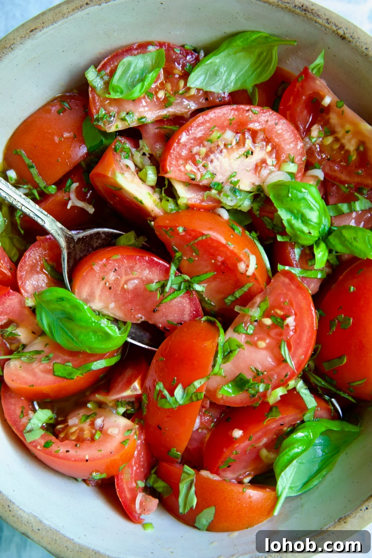 Quick-Pickled Marinated Tomatoes for Fresh Summer Flavor 2 Marinated Tomatoes in old clay bowl with serving spoon garnished with fresh parsley.