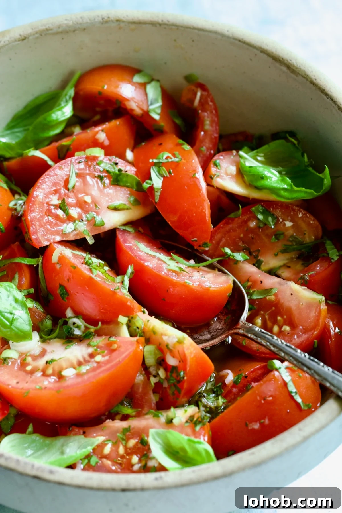 Quick-Pickled Marinated Tomatoes for Fresh Summer Flavor 11 Marinated Tomatoes in old clay bowl with serving spoon garnished with fresh parsley.