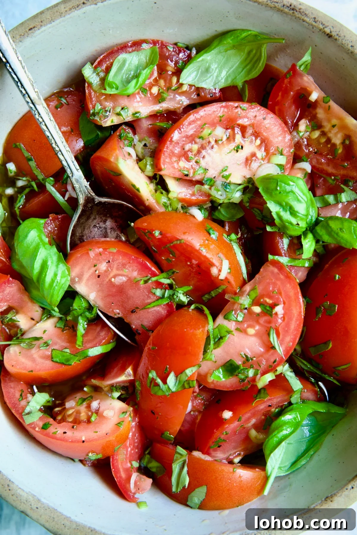 Quick-Pickled Marinated Tomatoes for Fresh Summer Flavor 12 Marinated Tomatoes in old clay bowl with serving spoon garnished with fresh parsley.