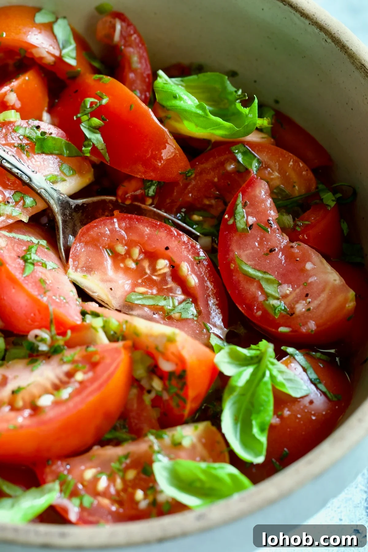 Quick-Pickled Marinated Tomatoes for Fresh Summer Flavor 3 Marinated Tomatoes in old clay bowl with serving spoon garnished with fresh parsley.