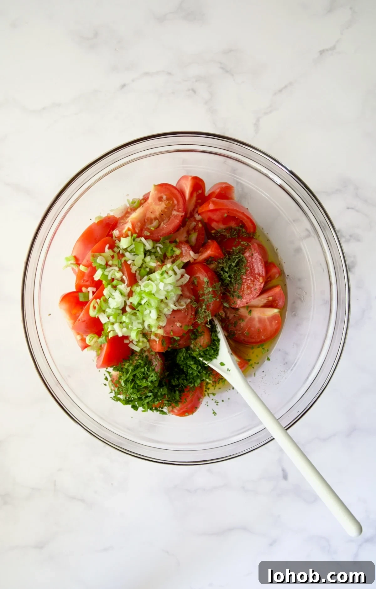 Quick-Pickled Marinated Tomatoes for Fresh Summer Flavor 8 Herbs and scallions added to tomato wedges in glass bowl.