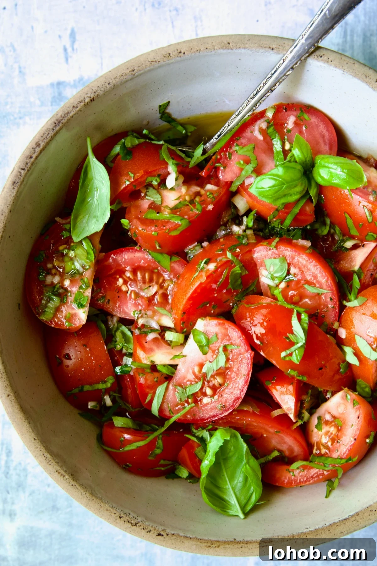 Quick-Pickled Marinated Tomatoes for Fresh Summer Flavor 10 Marinated Tomatoes in old clay bowl with serving spoon garnished with fresh parsley.