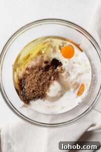A glass bowl with wet ingredients for a muffin recipe.