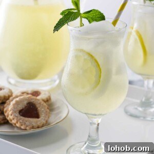 Classic Old-Fashioned Lemonade Recipe for Refreshing Summer Sips 7 A tray with glasses of old fashioned lemonade garnished with fresh mint, a pitcher of lemonade and a plate of cookies.
