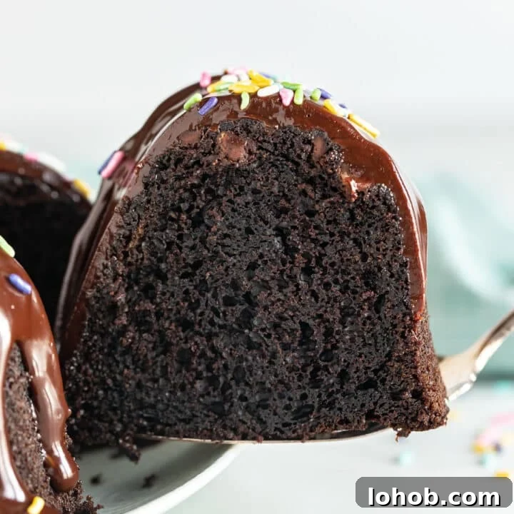 A piece of chocolate cake being pulled from the whole cake revealing the moist inside of the cake.