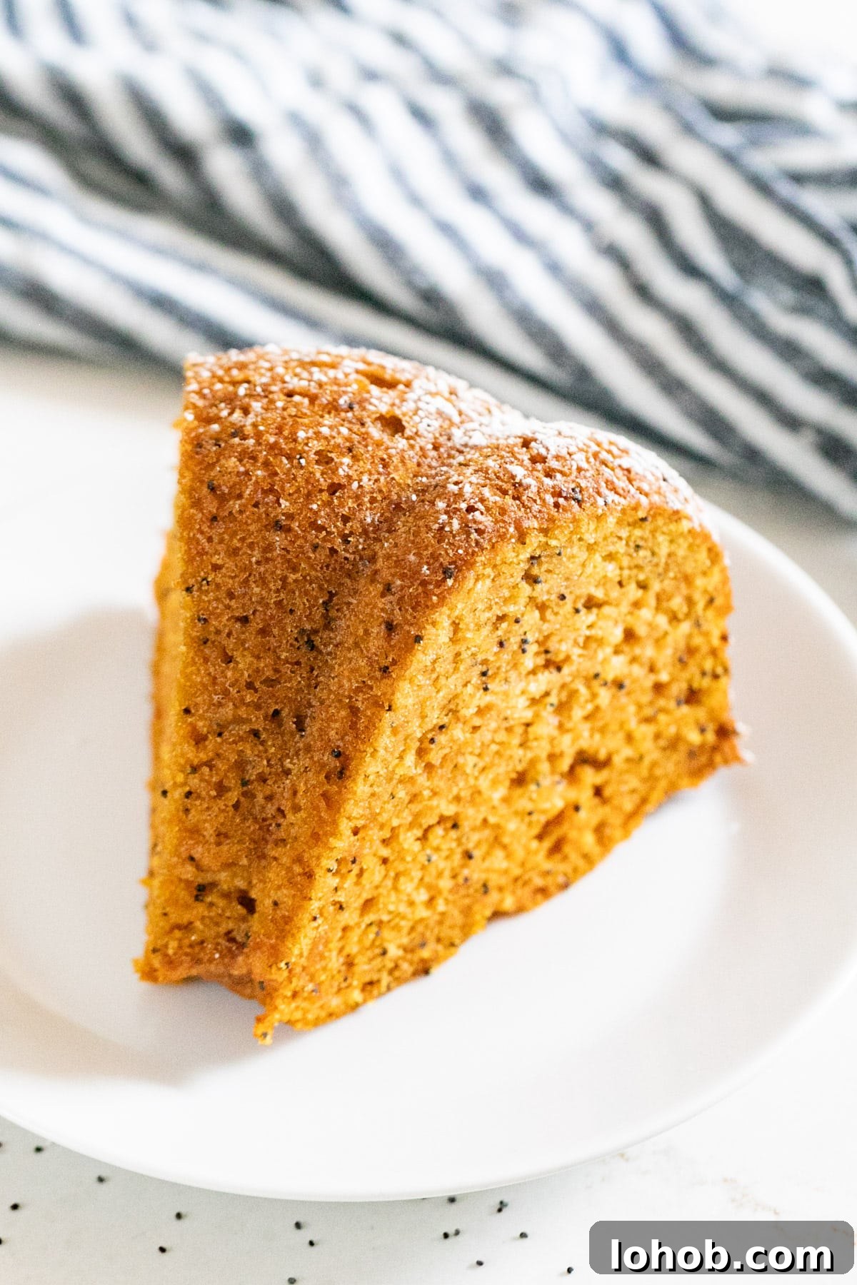 A slice of poppyseed cake on a white plate.