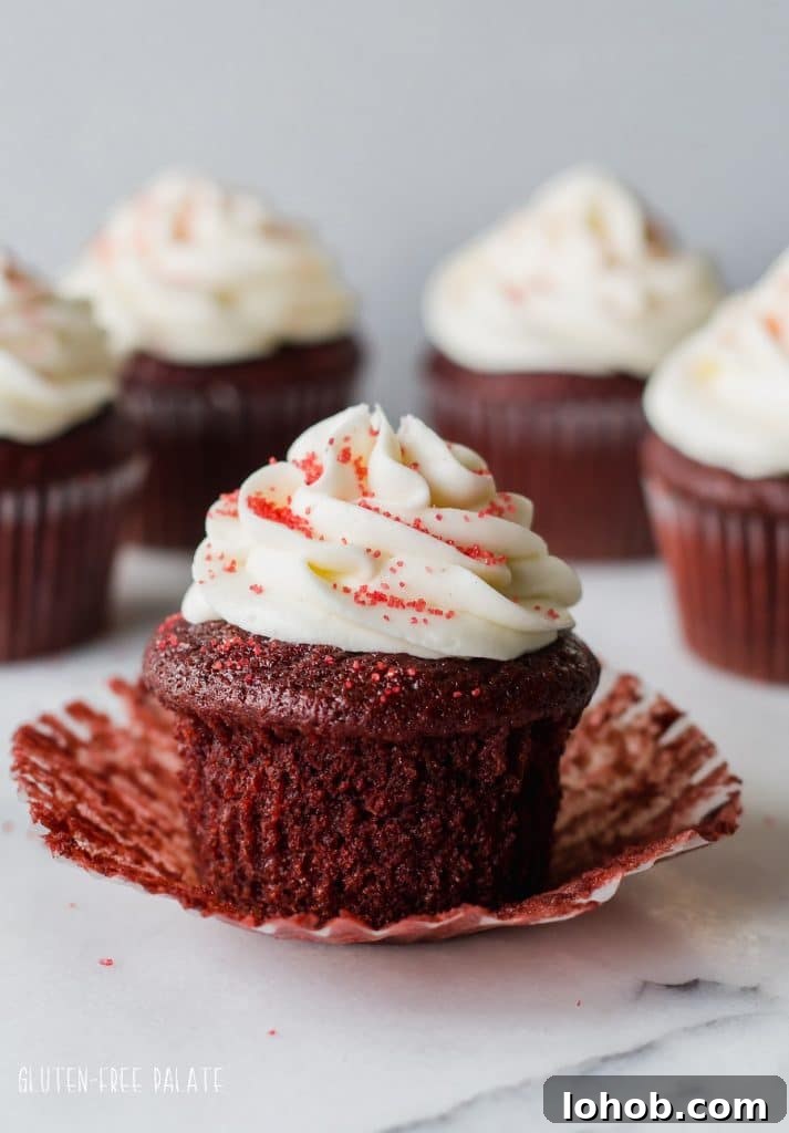 Gluten-Free Red Velvet Cupcakes Recipe for Moist, Fluffy Results 3 a gluten free red velvet cupcake topped with white frosting and red sugar, with the paper liner peeled down