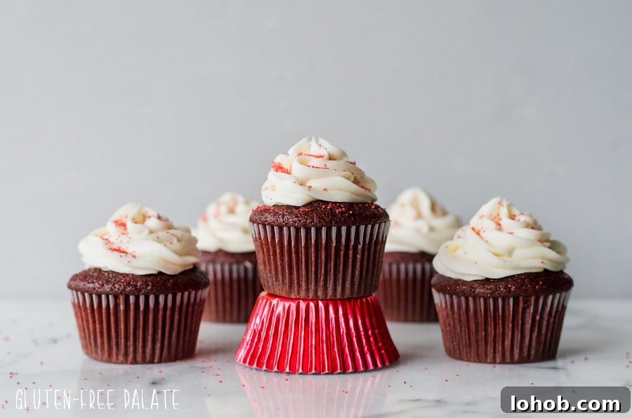 Gluten-Free Red Velvet Cupcakes Recipe for Moist, Fluffy Results 4 Gluten free red velvet cupcakes topped with white frosting and red sugar, one is sitting on a shiny red paper liner. Photo by Gluten-Free Palate.