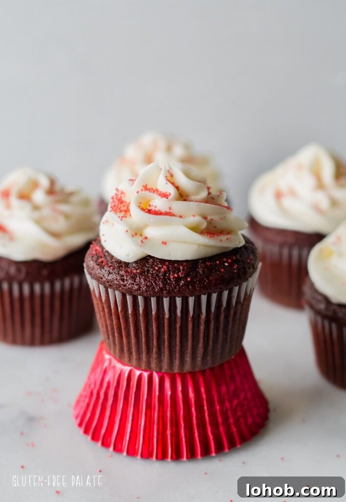 Gluten-Free Red Velvet Cupcakes Recipe for Moist, Fluffy Results 5 A close up of gluten free red velvet cupcakes topped with white frosting and red sugar, one is sitting on a shiny red paper liner. Photo by Gluten-Free Palate.