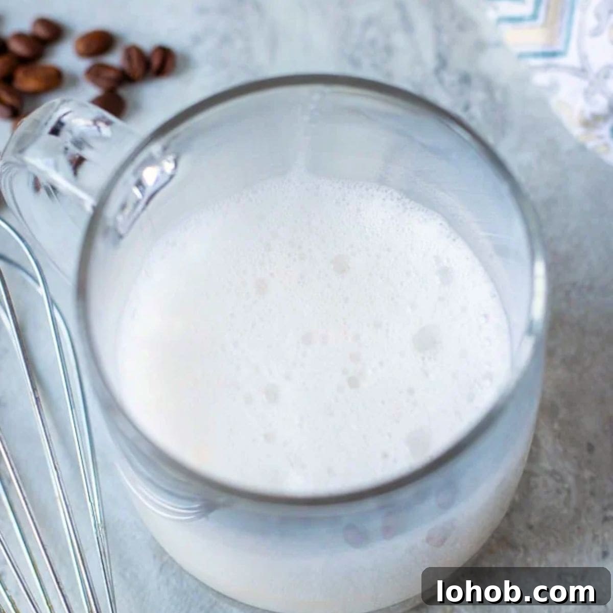 Warm milk whisked in glass mug for a latte.