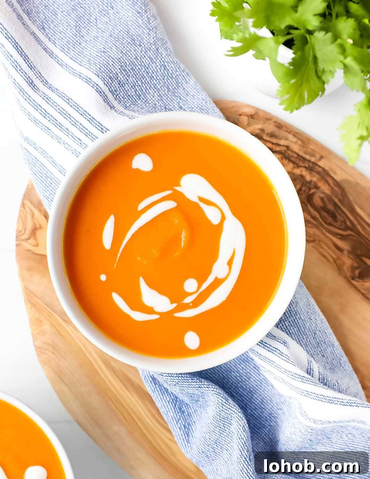 Creamy Carrot, Ginger and Coconut Soup 4 A bowl filled with bright orange soup with a coconut drizzle on top.
