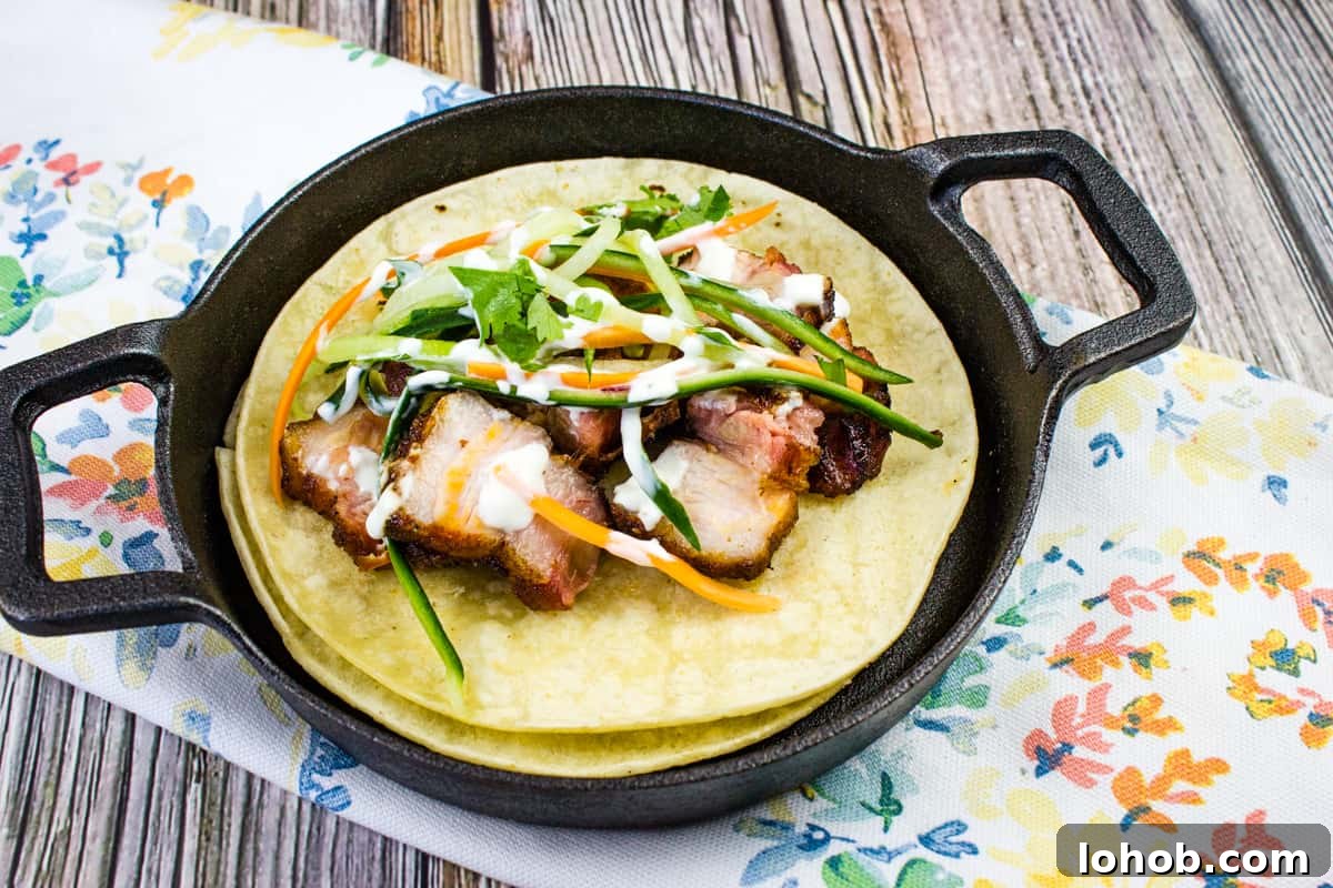 A closeup shot of two tacos filled with smoked pork belly and vegetables.
