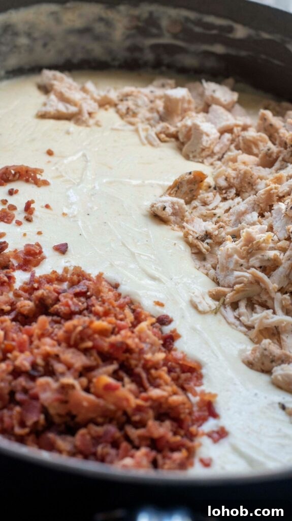 bacon and chicken with alfredo sauce in a pan