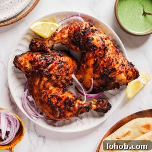 Crispy Air Fryer Tandoori Chicken Recipe 8 air fryer tandoori chicken on a plate sliced onions and lemon wedges.
