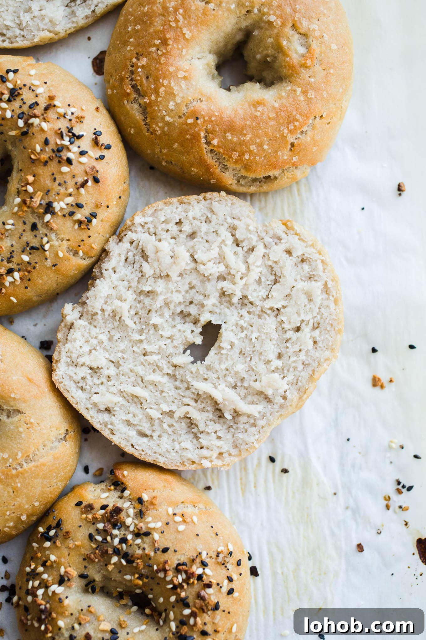 Vegan Gluten-Free Bagel Recipe: Homemade Soft & Chewy Bagels 6 Sliced bagels on parchment paper.