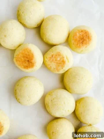 Cheesy bread rolls spread out on a piece of parchment paper.