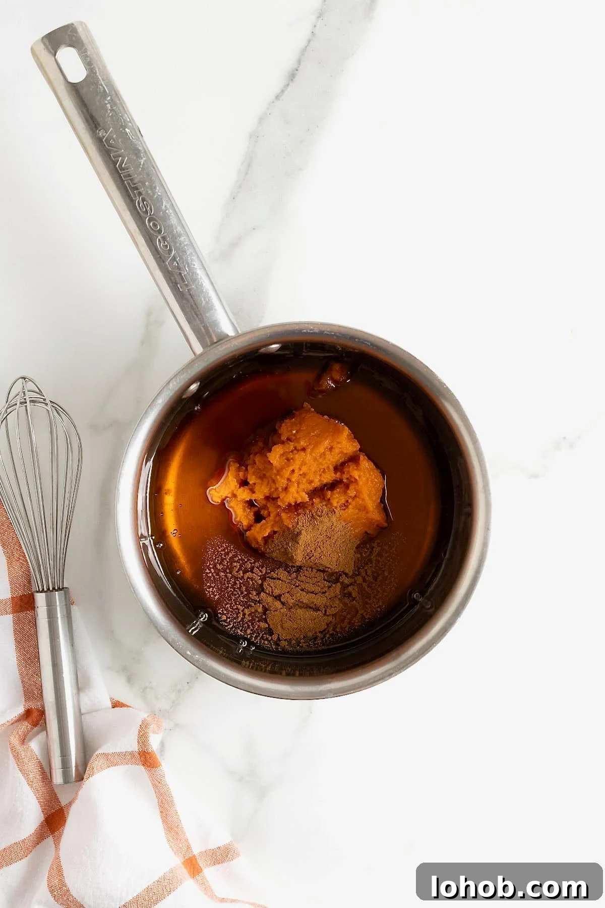 Pumpkin puree, maple syrup and pumpkin spice in a metal saucepan.