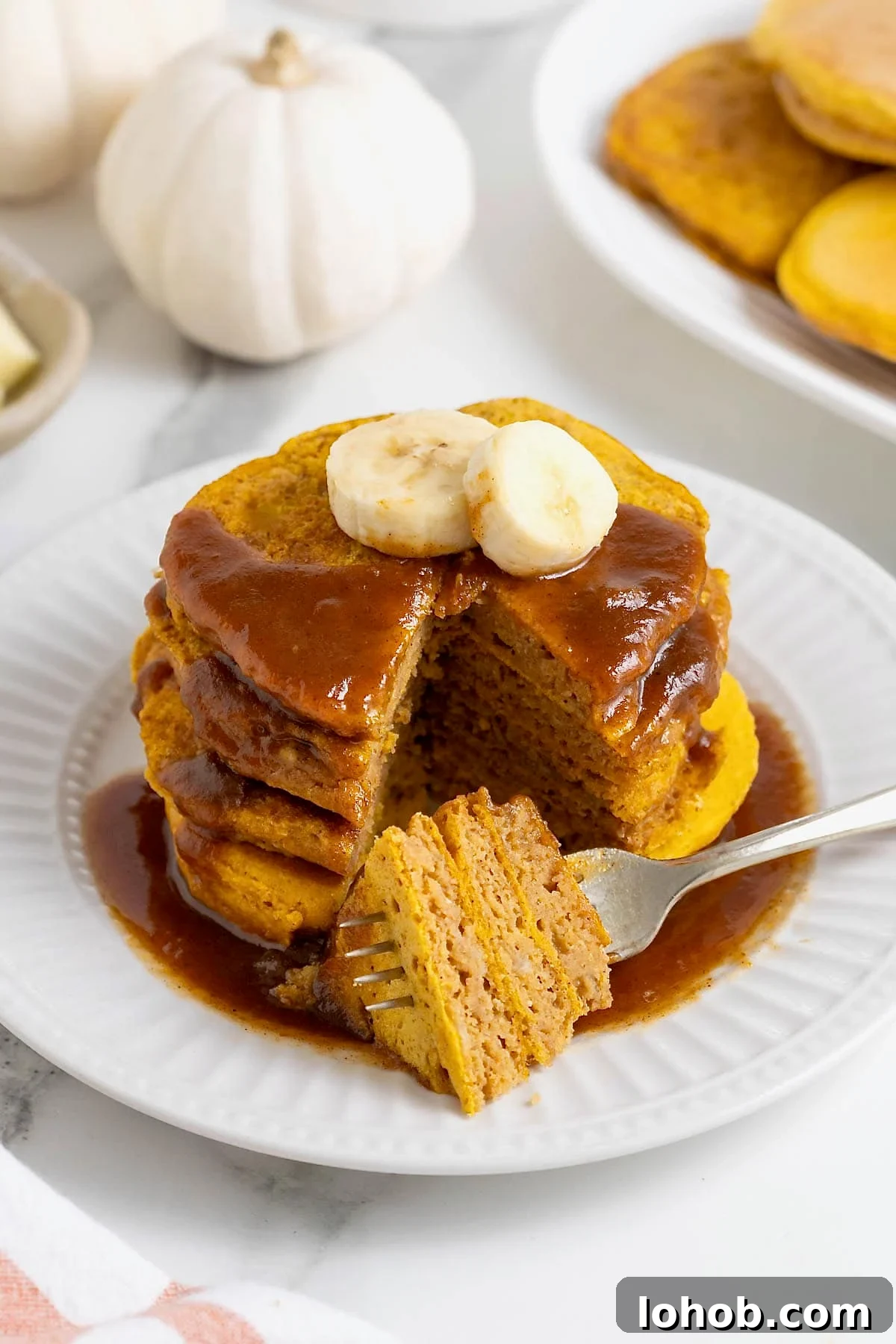 A stack of four pumpkin banana pancakes with a bite taken out.
